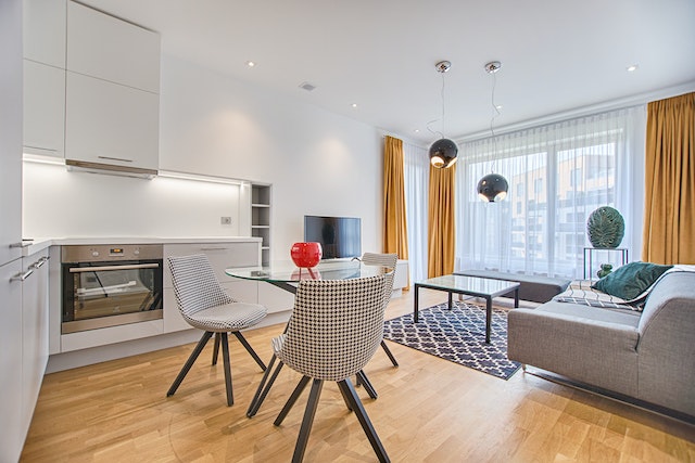 furnished apartment with round kitchen table, grey couch, tv, and square coffee table