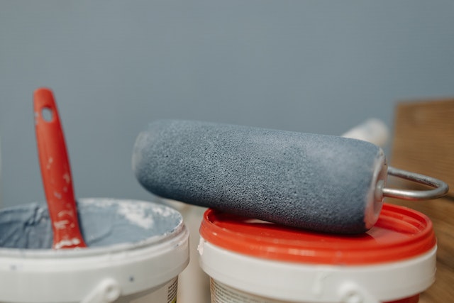 paint brush and roller with grey paint on them
