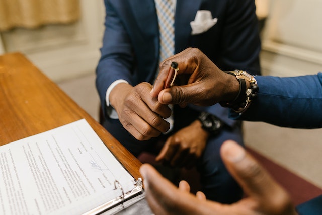 two people holding a pen over a contract