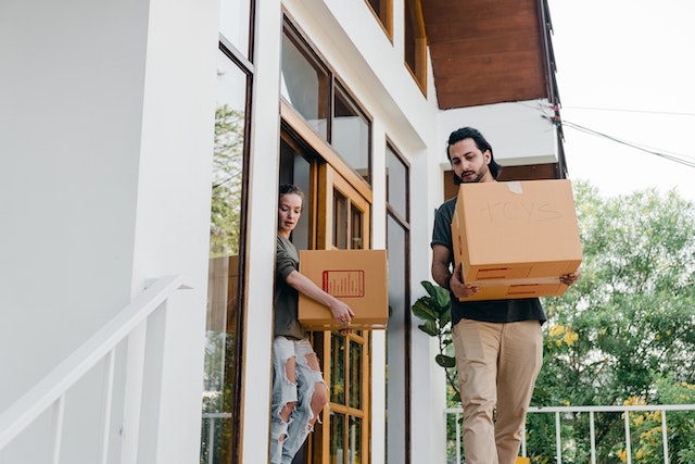 two people leaving a property with boxes