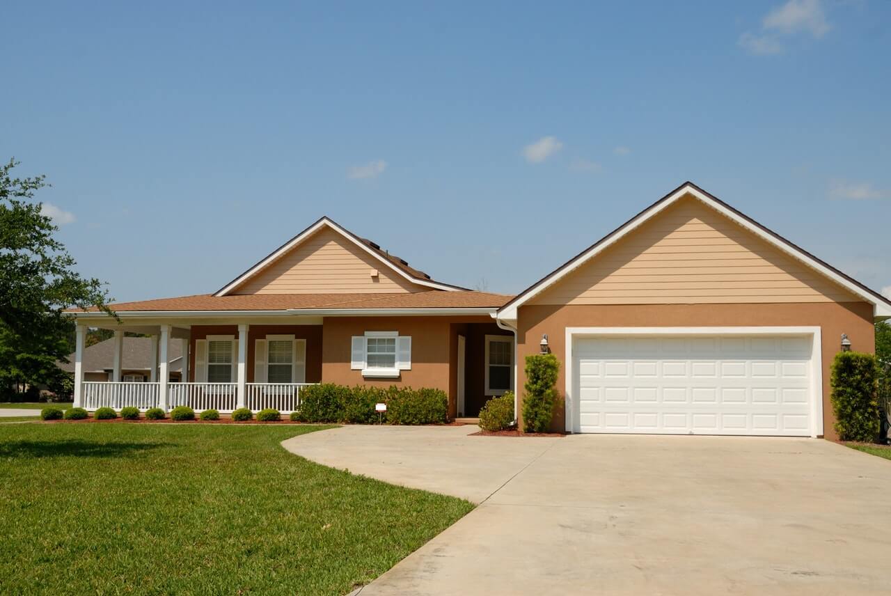 a brown and tan bungalow with a garage and a large veranda