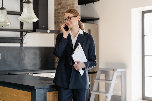 a real estate agent standing an property for sale talking on the phone